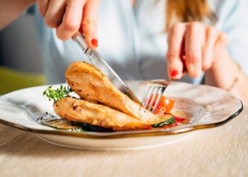 Eine Frau isst gegrillte Hähnchenbrust