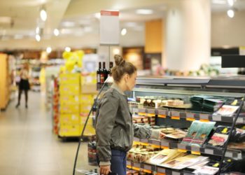 Eine Frau steht vor einem Regal im Supermarkt.