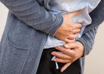 Eine Frau hält sich beide Hände auf den Bauch und den Unterleib.