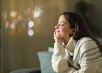 Entspannt lächelnde Frau sitzt auf dem Sofa