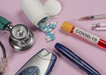 Eine Blutprobe mit der Aufschrift "COVID-19" liegt neben medizinischen Gegenständen, die bei Diabetes zum Einsatz kommen.