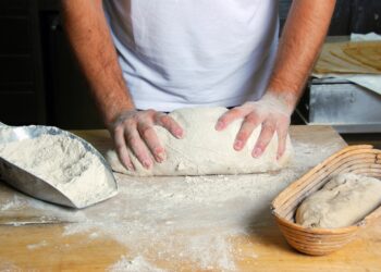 Bäcker knetet Brotteig auf einem Tisch