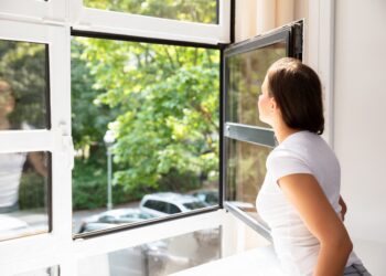 Frau öffnet Fenster zum Lüften