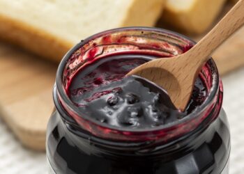 Ein Holzlöffel in einem Glas mit konservierten Heidelbeeren