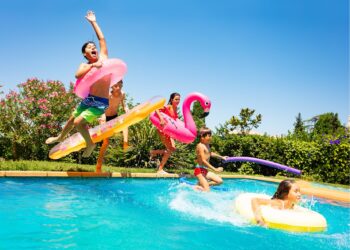 Fünf Kinder springen in einen Swimmingpool.