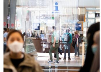 Menschen mit Mundschutz in einem öffentlichen Gebäude.