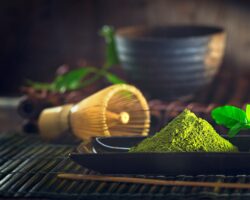 Ein schwarzes Schälchen mit Matcha-Pulver steht auf einem Tisch.