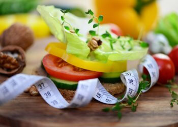 Ein mit Gemüse belegtes Vollkornbrot neben einem Maßband