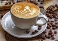 Eine Tasse Cafe Latte mit verziertem Milchschaum neben fischen Kaffeebohnen