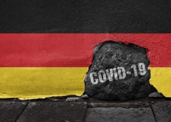 Eine Deutschlandfahne mit einem Loch in dem "COVID-19" steht.