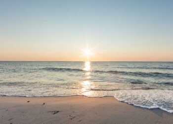 Strand am Meer mit Sonne am Horizont