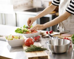 Frau bereitet einen gemischten Salat in einer Küche zu