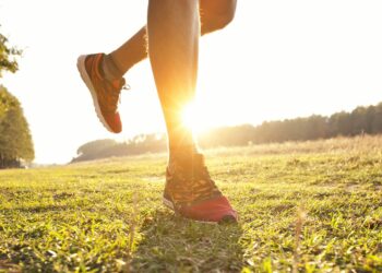 Junger Mann joggt querfeldein auf einer Wiese