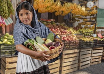 Frau hält Korb mit Obst und Gemüse.