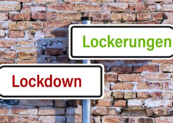 Zwei Straßenschilder: eins hat die Aufschrift "Lockdown", das andere die Aufschrift "Lockerungen".