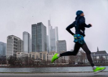 Ein Jogger läuft vor der Skyline von Frankfurt.