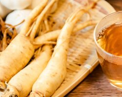 Ginseng-Wurzeln liegen neben einer Glastasse mit Ginsengtee