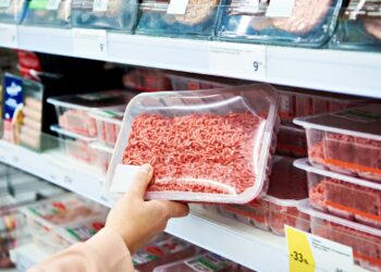 Eine Person nimmt eine Packung Hackfleisch aus einem Regal im Supermarkt.