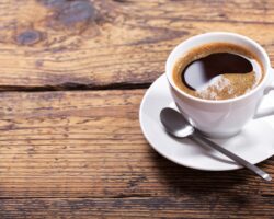 Eine Tasse schwarzer Kaffee mit einem Löffel auf einem Holztisch