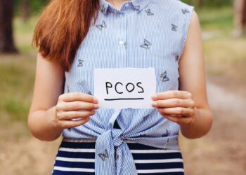 Frau hält einen Zettel mit der Aufschrift PCOS vor sich