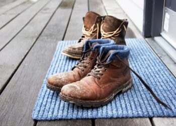 Schmutzige Stiefel stehen auf einem Fußabtreter.