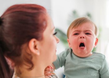 Eine Mutter hält ein hustendes Baby im Arm.