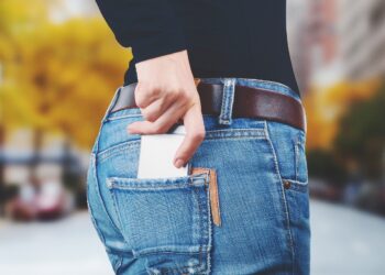 Frau steckt Smartphone in die Hosentasche.