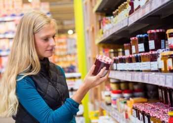 Junge Frau kauft Marmelade in einem Supermarkt.