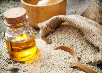 sesame seeds in sack and bottle of oil on wooden rustic table (Bild: chamillew /adobe.stock.com)