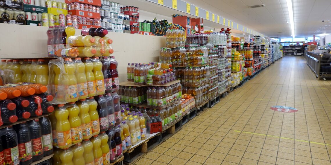 Lange Regale mit Getränken in Plastikflaschen in einem Supermarkt.