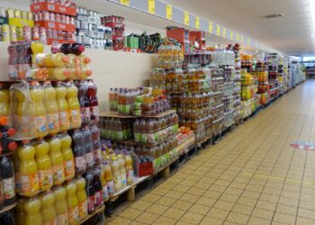 Lange Regale mit Getränken in Plastikflaschen in einem Supermarkt.