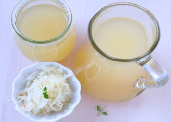Sauerkraut in einer Schale und zwei Kannen mit Sauerkrautsaft.