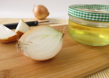 Eine aufgeschnittene Zwiebel neben einem Glas mit Zwiebelsaft