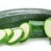 Zucchini und Zucchini-Scheiben vor weißem Hintergrund