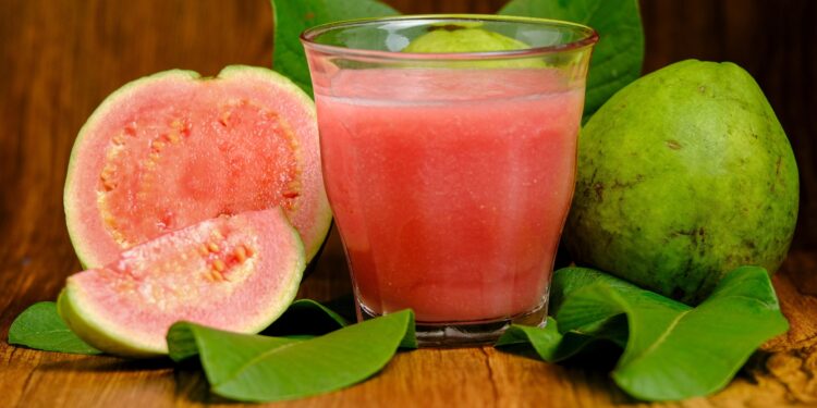 Guaven-Frucht und ein Glas mit Guavensaft in Großaufnahme.